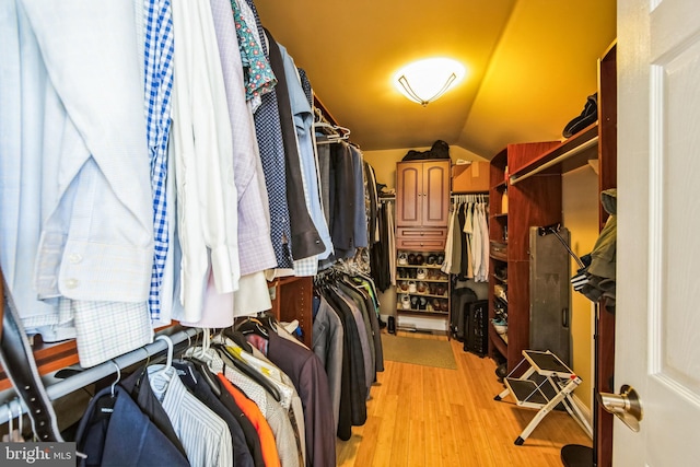 walk in closet with vaulted ceiling and light wood-style floors