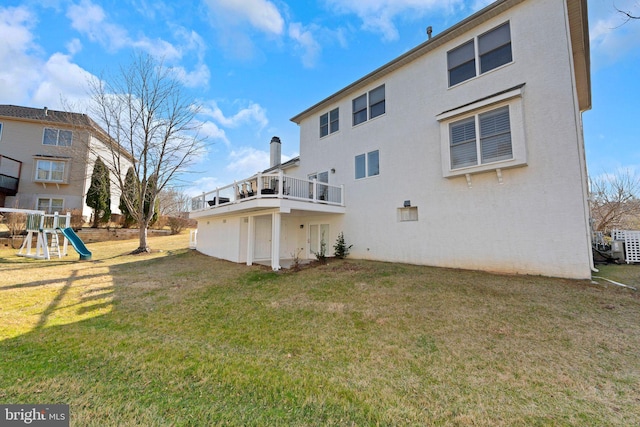 rear view of house featuring a playground, a yard, and stucco siding