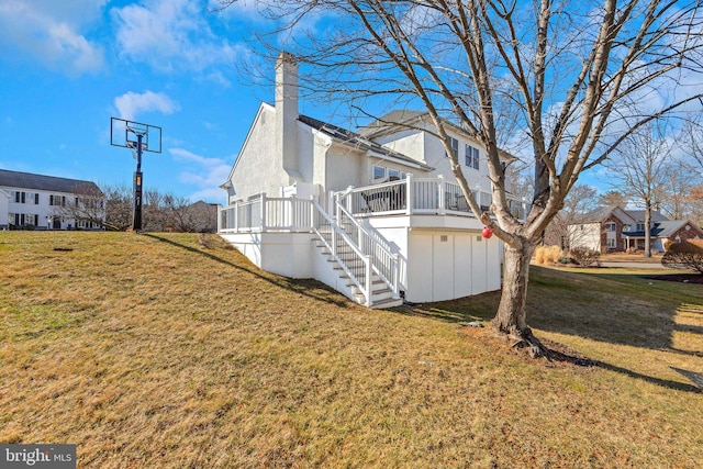 view of side of property with a lawn, a chimney, stairs, and a deck