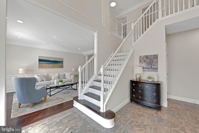 stairway with baseboards, a high ceiling, wood finished floors, and crown molding