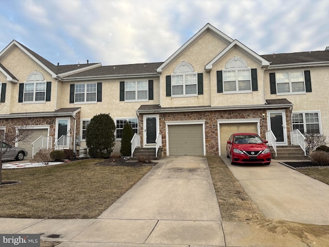 view of property featuring driveway, stone siding, a garage, and stucco siding