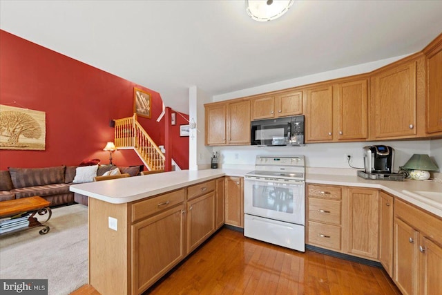 kitchen featuring black microwave, a peninsula, open floor plan, light countertops, and white electric range oven