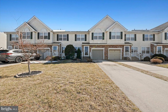 townhome / multi-family property featuring concrete driveway, stucco siding, an attached garage, and a front yard