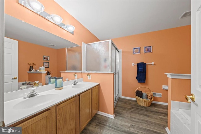 bathroom with wood finished floors, a stall shower, and a sink