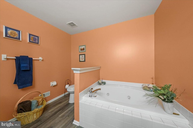 bathroom with visible vents, toilet, wood finished floors, a jetted tub, and baseboards