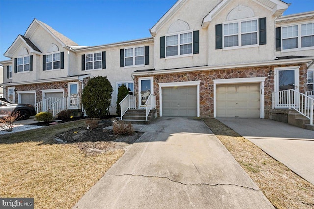 multi unit property with a garage, stone siding, concrete driveway, and stucco siding