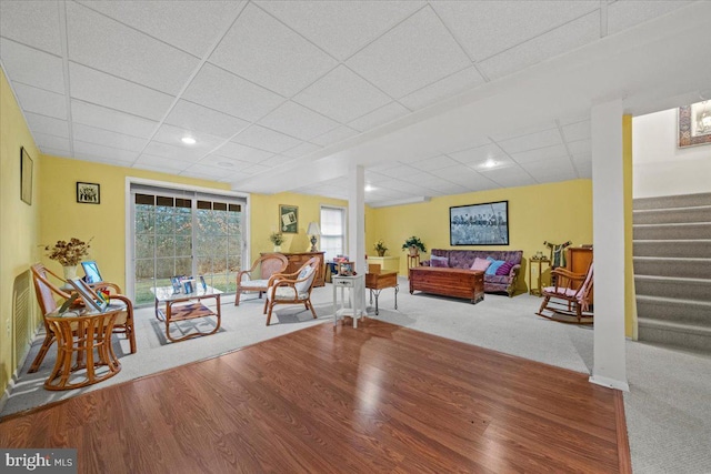 living area with a paneled ceiling, stairs, and wood finished floors