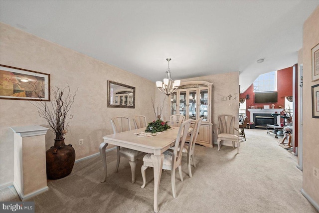 dining area with light carpet, baseboards, a glass covered fireplace, and a chandelier