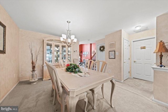 dining area with baseboards, an inviting chandelier, and light colored carpet