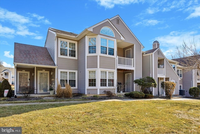 view of front of home with a front yard, cooling unit, and a balcony