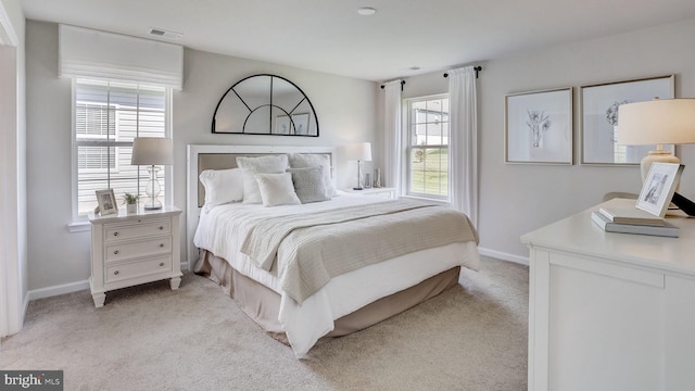 bedroom featuring baseboards, visible vents, and light colored carpet