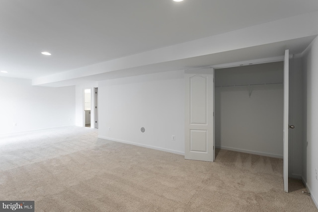 finished below grade area featuring baseboards, recessed lighting, and light colored carpet