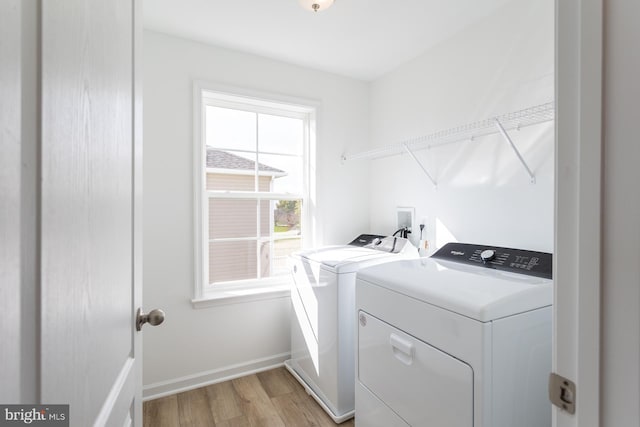 laundry area featuring light wood-type flooring, laundry area, baseboards, and washer and clothes dryer