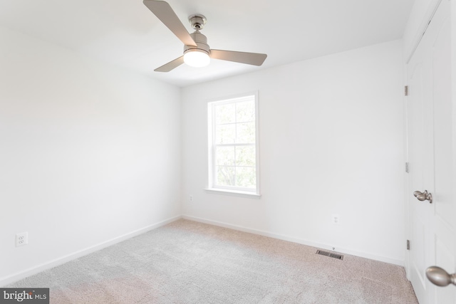 carpeted empty room featuring a ceiling fan, visible vents, and baseboards