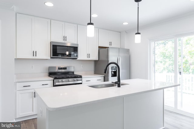 kitchen featuring stainless steel appliances, a sink, white cabinets, light countertops, and an island with sink