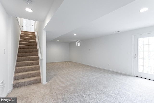 below grade area featuring recessed lighting, visible vents, light carpet, baseboards, and stairs