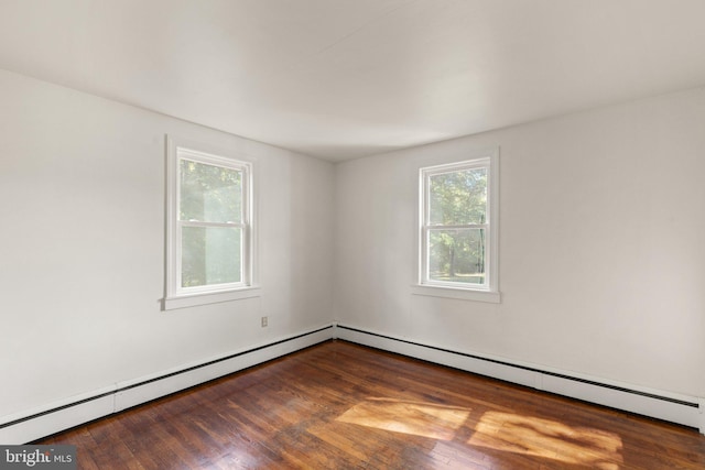 unfurnished room featuring a baseboard heating unit and wood finished floors