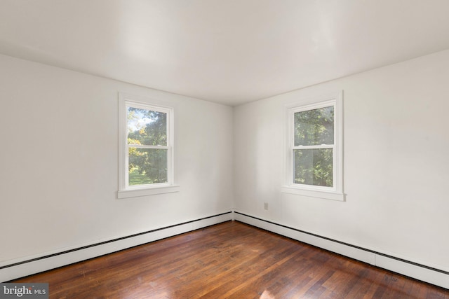 spare room with dark wood-style floors, a baseboard radiator, and a healthy amount of sunlight