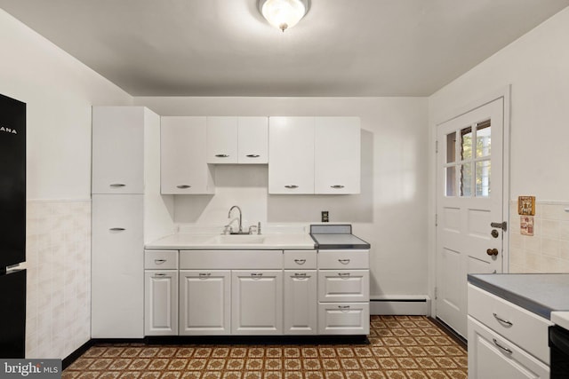 kitchen featuring white cabinets, a baseboard radiator, dark floors, light countertops, and a sink