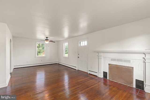 unfurnished living room with a baseboard heating unit, a brick fireplace, wood finished floors, and visible vents