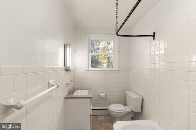 bathroom with a baseboard heating unit, vanity, toilet, and tile walls