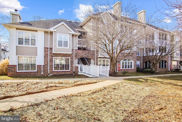 view of front of home with a gate, brick siding, fence, and a chimney