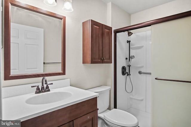 bathroom featuring toilet, a shower stall, and vanity