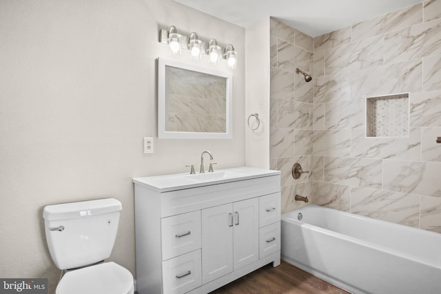 bathroom featuring toilet, vanity, wood finished floors, and shower / bathing tub combination