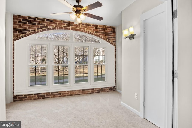 interior space featuring brick wall, carpet flooring, and a ceiling fan