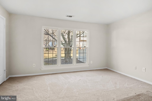 carpeted spare room with visible vents and baseboards