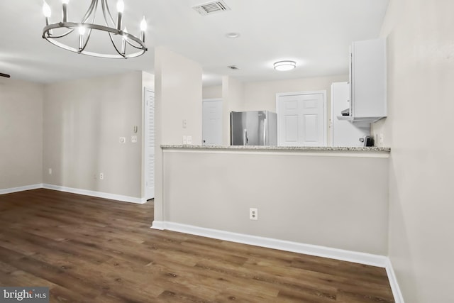 interior space featuring visible vents, baseboards, freestanding refrigerator, and white cabinetry