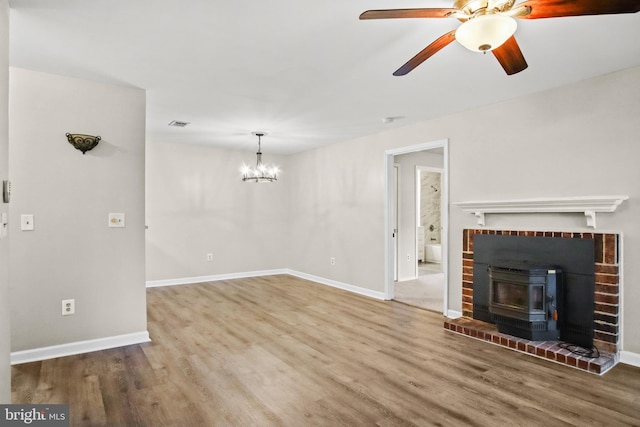 unfurnished living room featuring ceiling fan with notable chandelier, wood finished floors, and baseboards