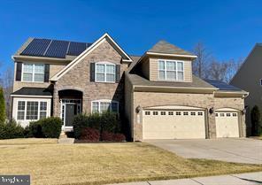 13010 Davenport Dr, Brandywine, MD 20613 - traditional-style house with roof mounted solar panels, driveway, stone siding, and an attached garage