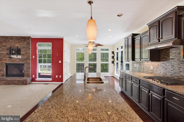 13010 Davenport Dr, Brandywine, MD 20613 - kitchen featuring stainless steel gas cooktop, a sink, baseboards, light stone counters, and under cabinet range hood