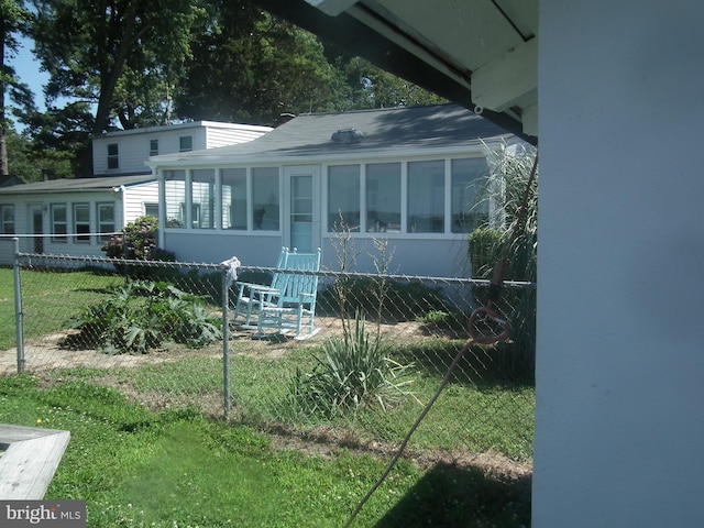 view of front of home with a sunroom, fence, and a front lawn