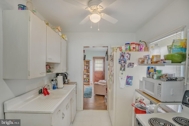 kitchen featuring white cabinetry, light countertops, stove, and white microwave