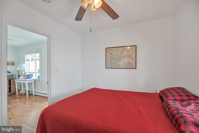 bedroom featuring ceiling fan, baseboard heating, and hardwood / wood-style floors