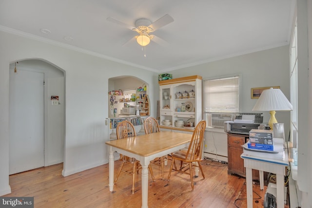 dining area with a baseboard heating unit, arched walkways, ornamental molding, and light wood finished floors