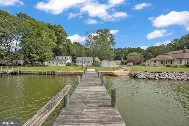 view of dock featuring a water view and a yard