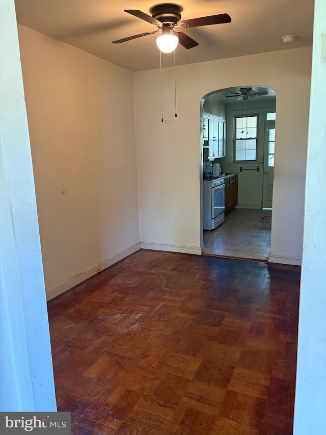 spare room featuring a ceiling fan, arched walkways, a smoke detector, and baseboards