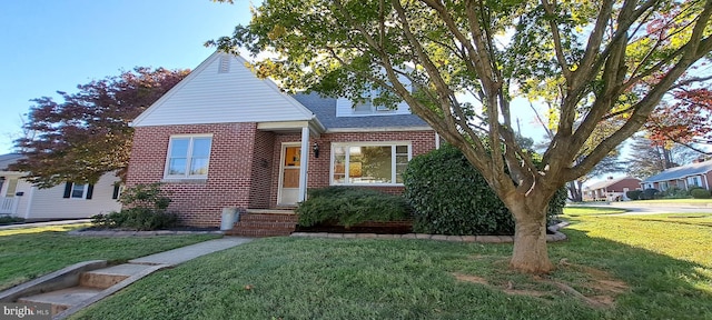 view of front of house with a shingled roof, brick siding, and a front lawn