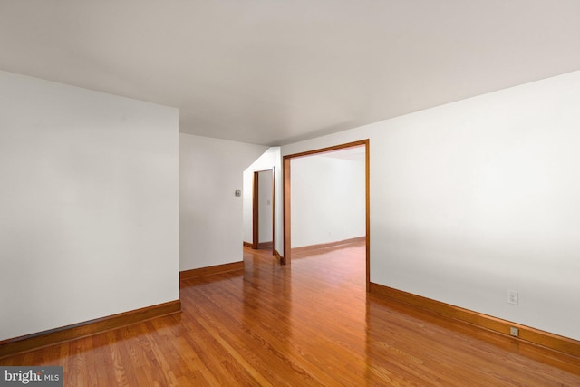 spare room with baseboards and wood finished floors