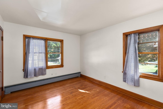 unfurnished room featuring a baseboard radiator, baseboards, plenty of natural light, and light wood finished floors