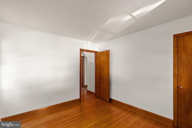 empty room featuring light wood-type flooring and baseboards