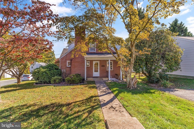 view of front of house with a porch, brick siding, a chimney, and a front yard