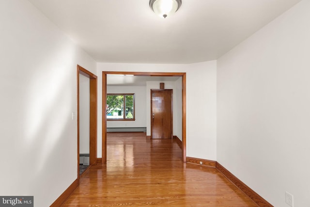 hall with light wood-type flooring, baseboards, and a baseboard heating unit