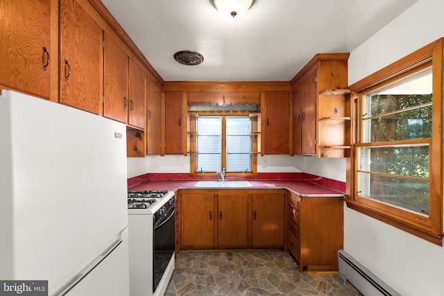 kitchen featuring brown cabinets, a baseboard radiator, stone finish flooring, a sink, and white appliances