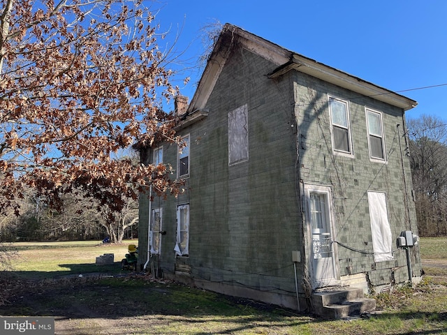 view of side of home featuring a chimney and a yard