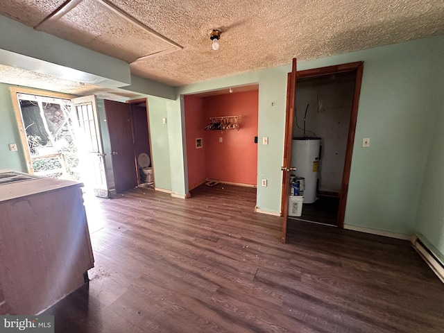 unfurnished bedroom featuring water heater, a baseboard heating unit, a textured ceiling, wood finished floors, and baseboards