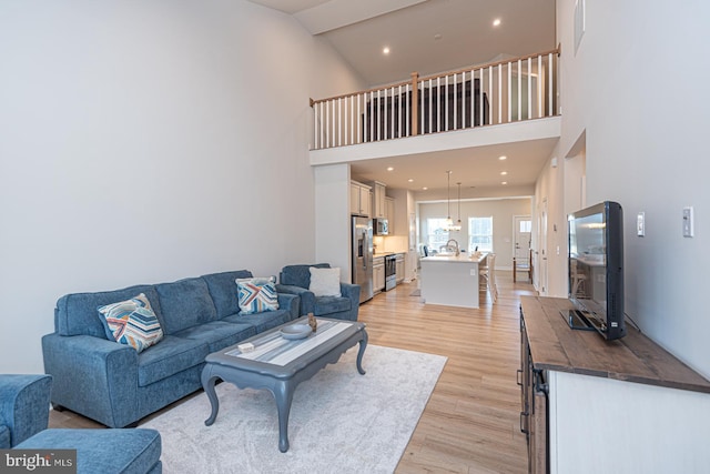 living room featuring a towering ceiling, light wood-style flooring, and recessed lighting